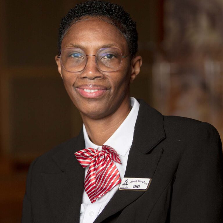 Professional black woman in black suit, white jacket and red bowtie.