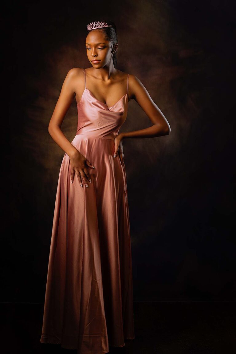 Beautiful black girl with long hair, in a pink prom dress and tiara.