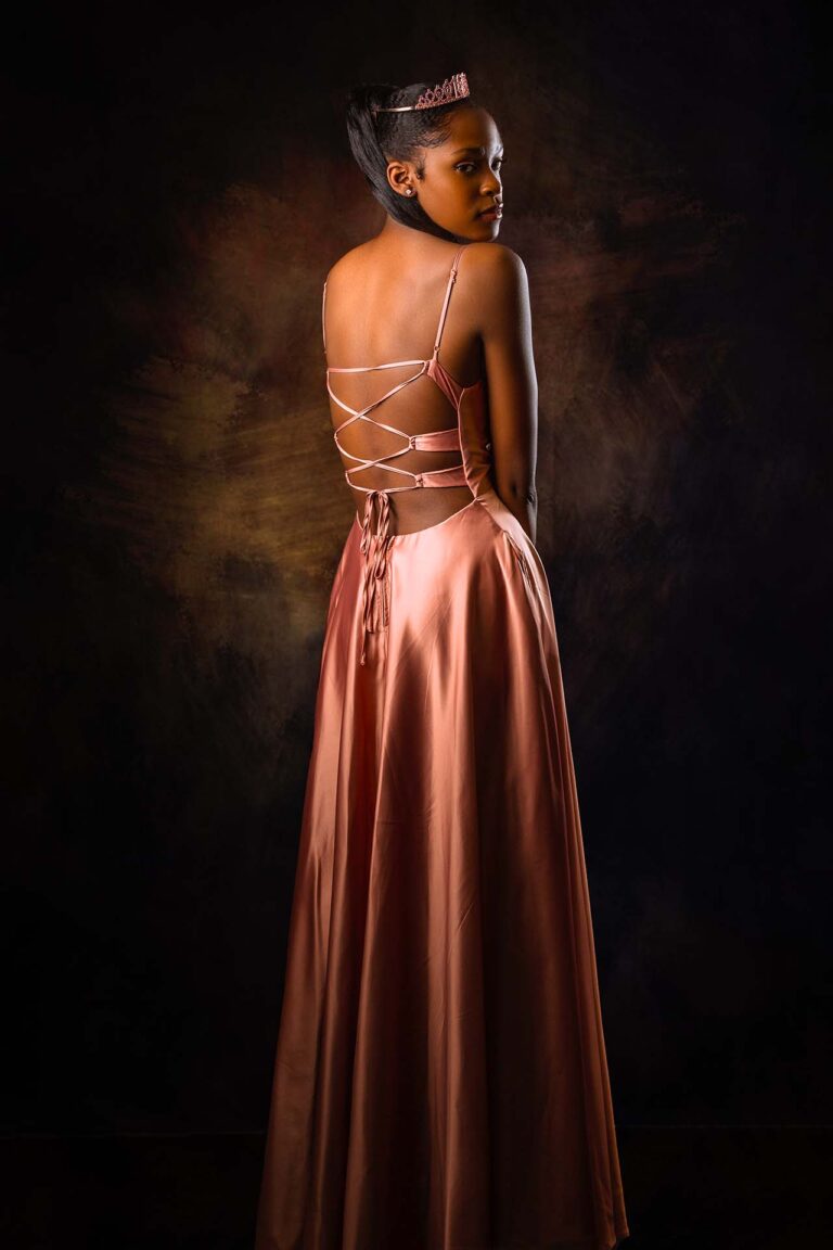 Beautiful black girl with long hair, in a pink prom dress and tiara.